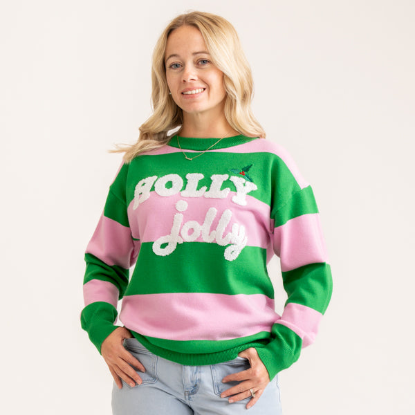 A woman wearing a green and pink striped crewneck sweater with 'HOLLY jolly' written in white across the front, paired with light blue jeans, against a plain off-white background.