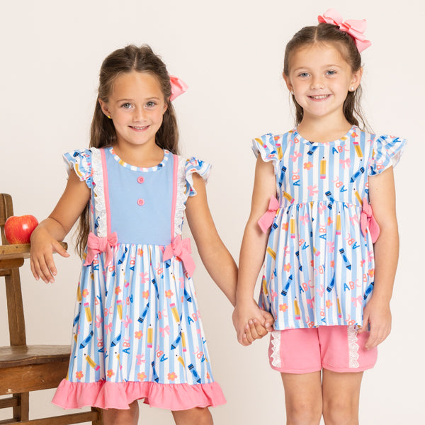 two girls wearing back to school matching sibling set