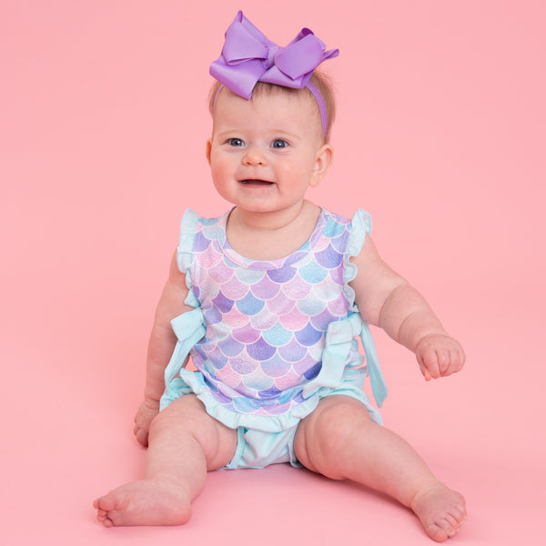 baby wearing mermaid bubble romper against pink background