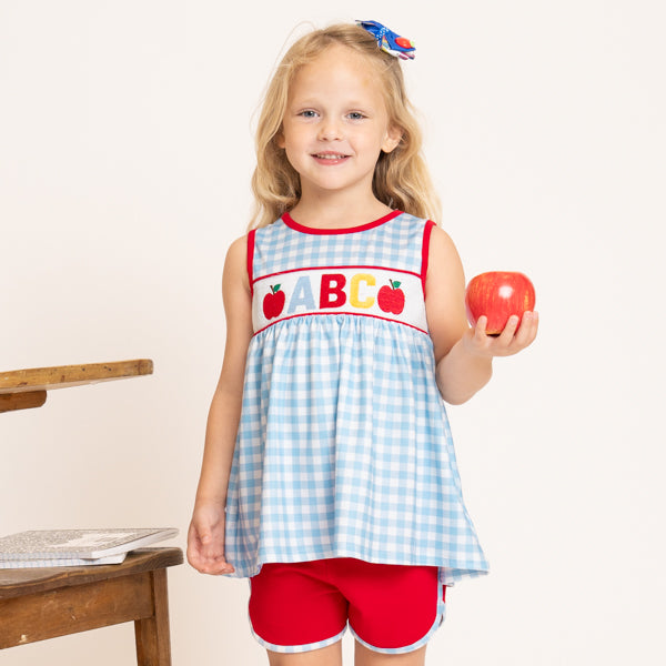 young girl in school outfit holding apple